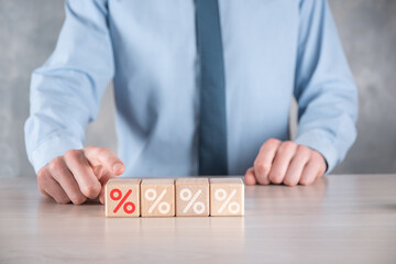 Businessman hand takes a wooden cube block depicting,shown the percentage symbol icon. Interest rate financial and mortgage rates concept.
