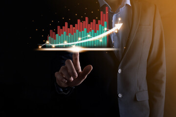 Businessman holding and showing a growing virtual hologram of statistics, graph and chart with arrow up on dark background. Stock market. Business growth, planing and strategy concept.