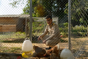 A Thai government officer, Civil servant is sitting in front of the chicken coop, henhouse.