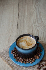 Сoffee in a blue cup and coffee beans on a wooden background