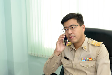 A Thai government officer, Civil servant is making a phone call at the office.