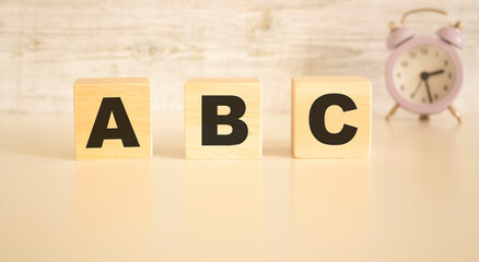 The word ABC consists of wooden cubes with letters, top view on a light background.