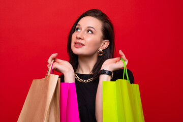 A young woman with colorful shopping bags on a red background