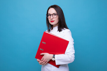 Fototapeta premium Portrait of a female doctor with a red folder on a blue background