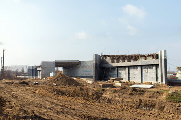 Fototapeta na wymiar Construction site with new concrete building structure and earthworks, bridge crossing