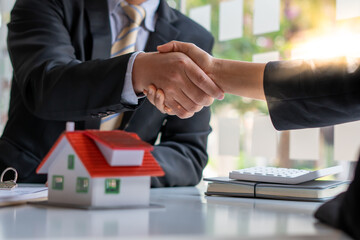 Real estate broker and customer shaking hands after signing a contract: real estate, home loan and...