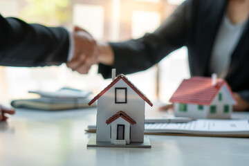 Real estate broker and customer shaking hands after signing a contract: real estate, home loan and insurance concept
