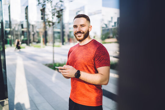 Positive man with smartphone on street