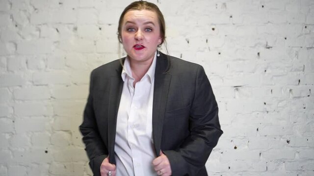 A plus-size woman in a man's suit speaks aggressively. Emotions of rage and aggression. The concept of feminism and the struggle for the rights of women.