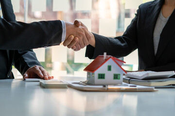 Real estate broker and customer shaking hands after signing a contract: real estate, home loan and insurance concept