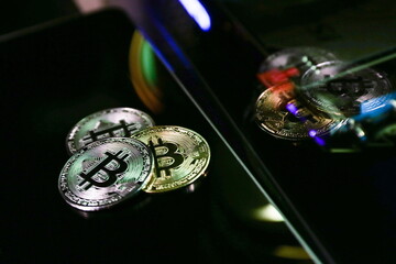 three bitcoin coins are on dark background with reflection