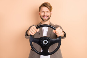 Photo of optimistic nice blond hair man hold wheel wear grey jacket isolated on beige background