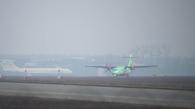A passenger plane goes to the airport. The airplane with the propellers goes to the terminal on the takeoff and landing sum for takeoff.