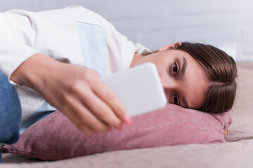 Obraz na płótnie Canvas sad teenage girl using smartphone in blurred foreground