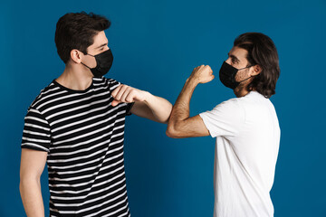 White brunette two men in face mask elbow bumping