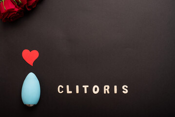 Clitoral vibrator, heart and a bouquet of scarlet roses on a black background. Copy space. - obrazy, fototapety, plakaty