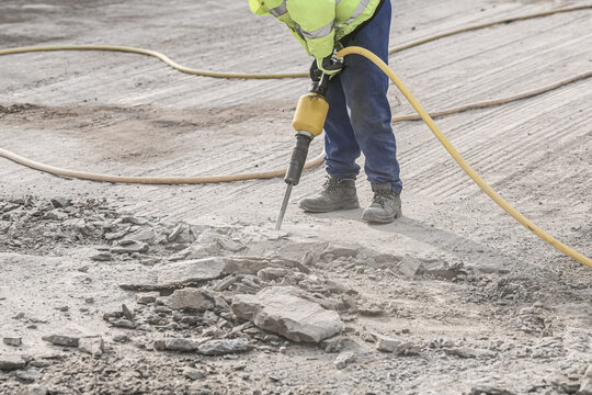 Demolition hammer. Male working in construction industry. Repairing and building a new road.