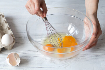 Fototapeta na wymiar Female hands whipping eggs, making homemade muffins, cookies or cake