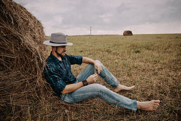 Naklejka na ściany i meble A man in a hat next to a haystack