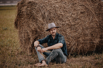 A man in a hat next to a haystack