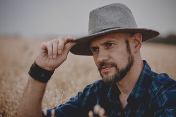 A man in a hat next to a haystack