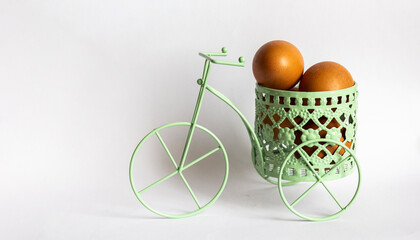Fototapeta na wymiar Green toy bike with colored eggs in basket on white background