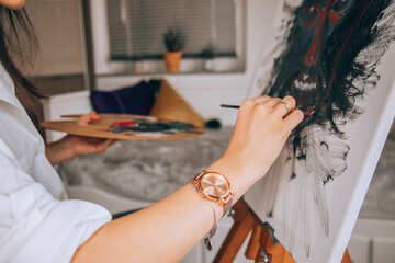 Beautiful talented female artist painting at her home.