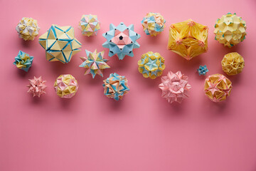 Set of multicolor handmade modular origami balls or Kusudama Isolated on pink background. Visual art, geometry, art of paper folding, paper crafts. Top view, close up, selective focus, copy space.