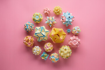 Set of multicolor handmade modular origami balls or Kusudama Isolated on pink background. Visual art, geometry, art of paper folding, paper crafts. Top view, close up, selective focus, copy space.
