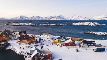 Breathtaking bird's eye view of Lofoten fishing village with red Traditional Norwegian houses. Aerial view from drone of panoramic island landscape with small city infrastructure between fjords..