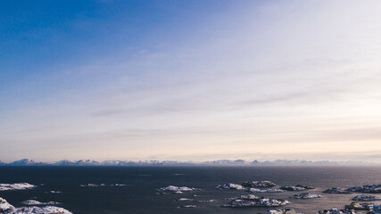Breathtaking bird's eye view of majestic fjord mountains covered with snow in winter. Aerial view of scenery rock peaks, picturesque beautiful nature landscape. Lofoten Island surrounds by Nordic sea