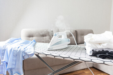 Steam blue iron on ironing board.  Hot electric iron. Clothes, ironing board household concept.