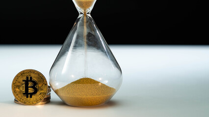 Gold Bitcoin and hourglass on white table with black background. Macro shot. Time is money, Etherium, Litecoin, Ripple, Xrp, Dogecoin, Defi