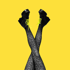 New gray female boots with bright yellow laces on long slender crossed woman legs in gray tights isolated on yellow background. Square Banner