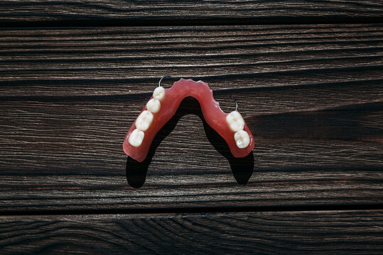 Dentures on a dark background. Close-up of dentures. Dentistry is conceptual photography. Prosthetic dentistry. False teeth. Prosthetics. Close-up of plastic dentures. Teeth on a wooden background