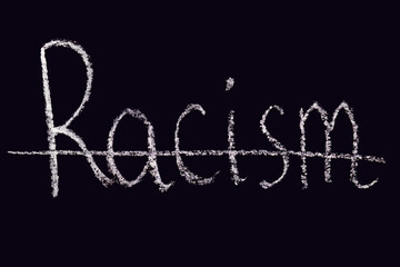 The crossed out word racism written in chalk on a black board