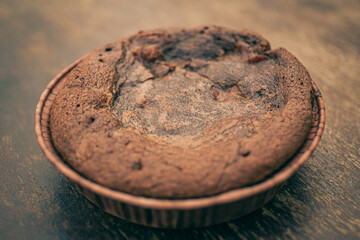 Close up of a rustic homemade mini chocolate cake on a wooden table.