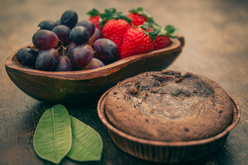 Delicious fruits and a mini chocolate cake on a wooden table. Gourmet.
