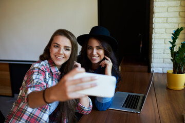Two cheerful women taking selfie on smartphone