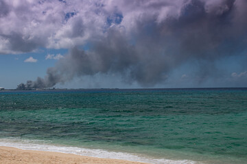 Fototapeta na wymiar A selective focus shot of thick black smoke rising from the Caribbean island of Grand Cayman due to the government dump catching on fire 