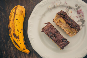 Banana cake with chocolate sauce on the top on a white plate. Top view.
