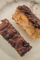 Banana cake with chocolate sauce on the top on a white plate. Top view.