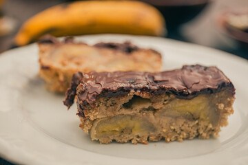 Banana cake with chocolate sauce on the top on a white plate.