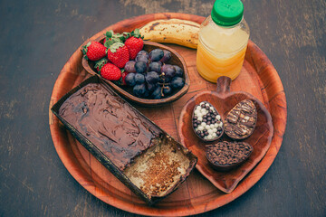 Simple, rustic and romantic breakfast board with fruit, chocolate and juice on a wooden table.
