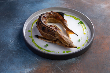 Fried sturgeon fish in a plate. Close-up.