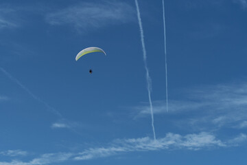 View of paraglider over bluish sky with clouds.