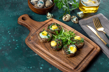 Baked champignons with quail eggs and microgreen garnish on a wooden cutting board