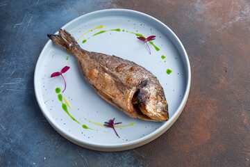 Fried dorado fish in a plate.