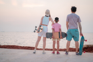 Family portrait, beach vacation, parents and children resting from skating, surfing, standing smiling happily.