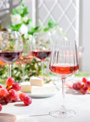 Roze wine in a glass on a light concrete background in the rays of the sun.